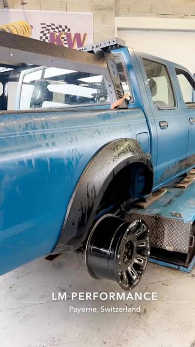 Un camion bleu est remorqué par une dépanneuse dans un garage.