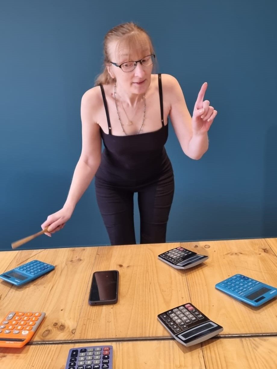 Femme debout devant un bureau avec des calculatrices posées dessus