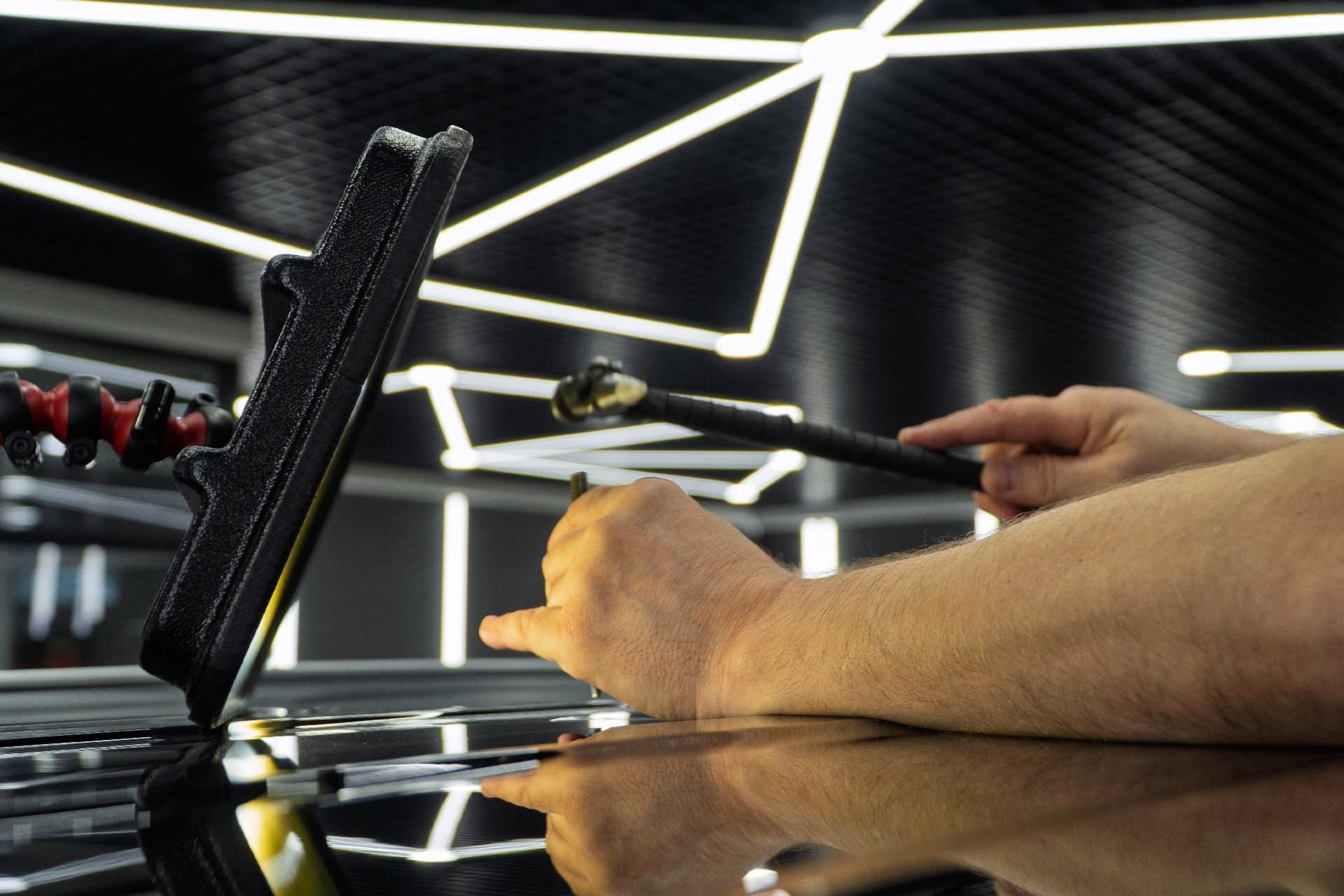 Eine Person untersucht ein Auto auf einen Hagelschaden