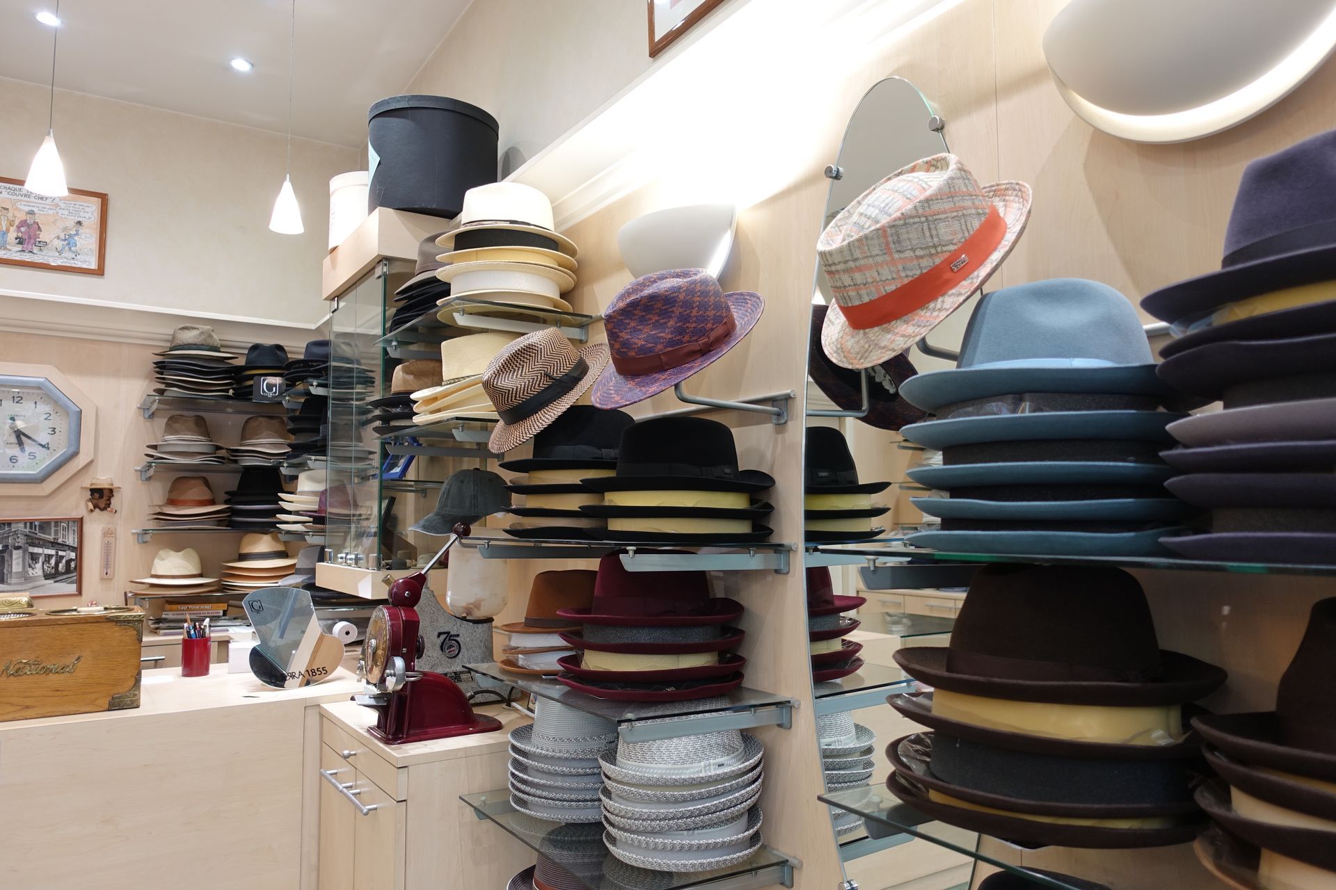 Allée du magasin avec des chapeaux et des casquettes empilés sur des étagères et des présentoirs.