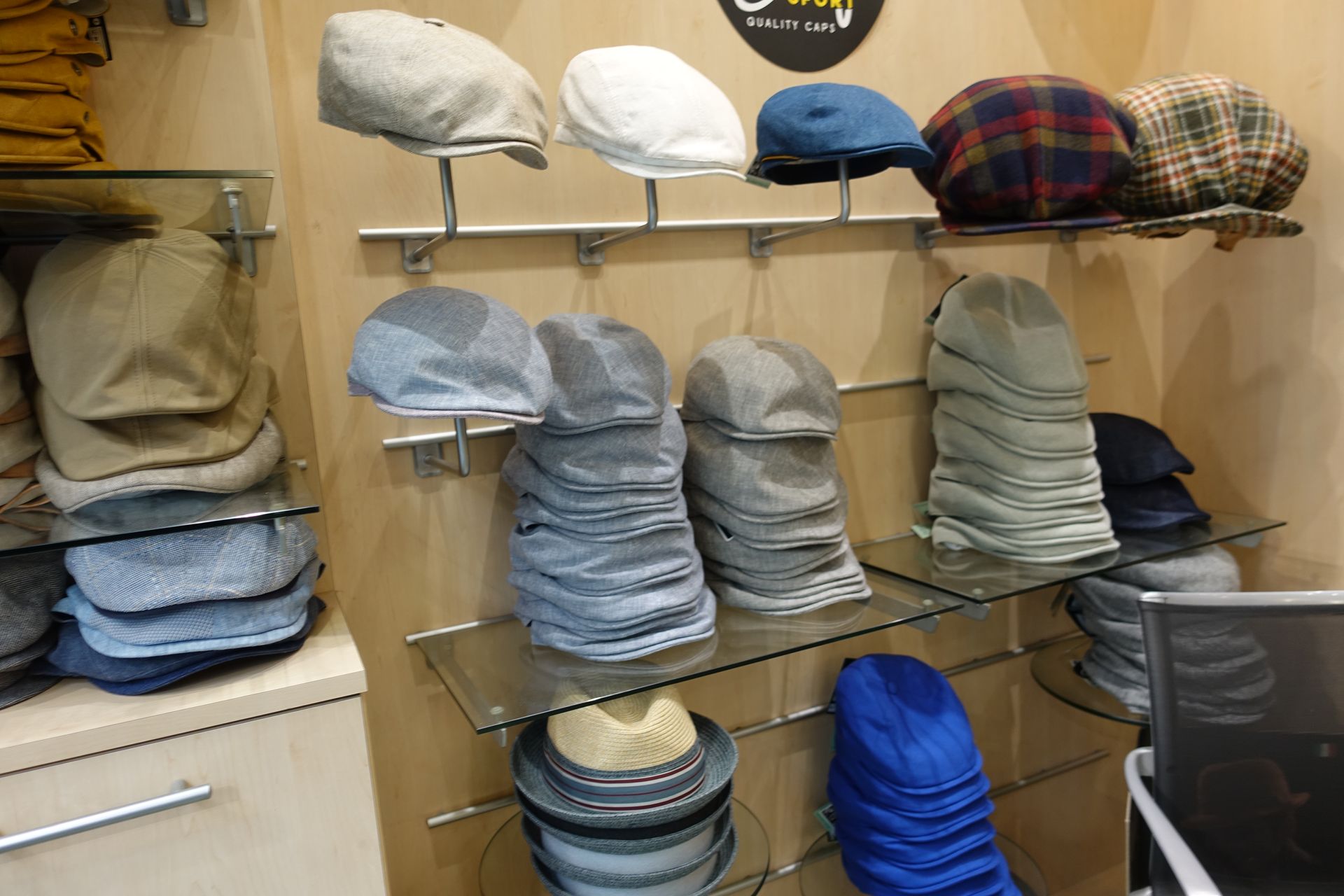 Des étagères présentent des chapeaux et des casquettes de différentes couleurs empilés à l'intérieur d'un magasin