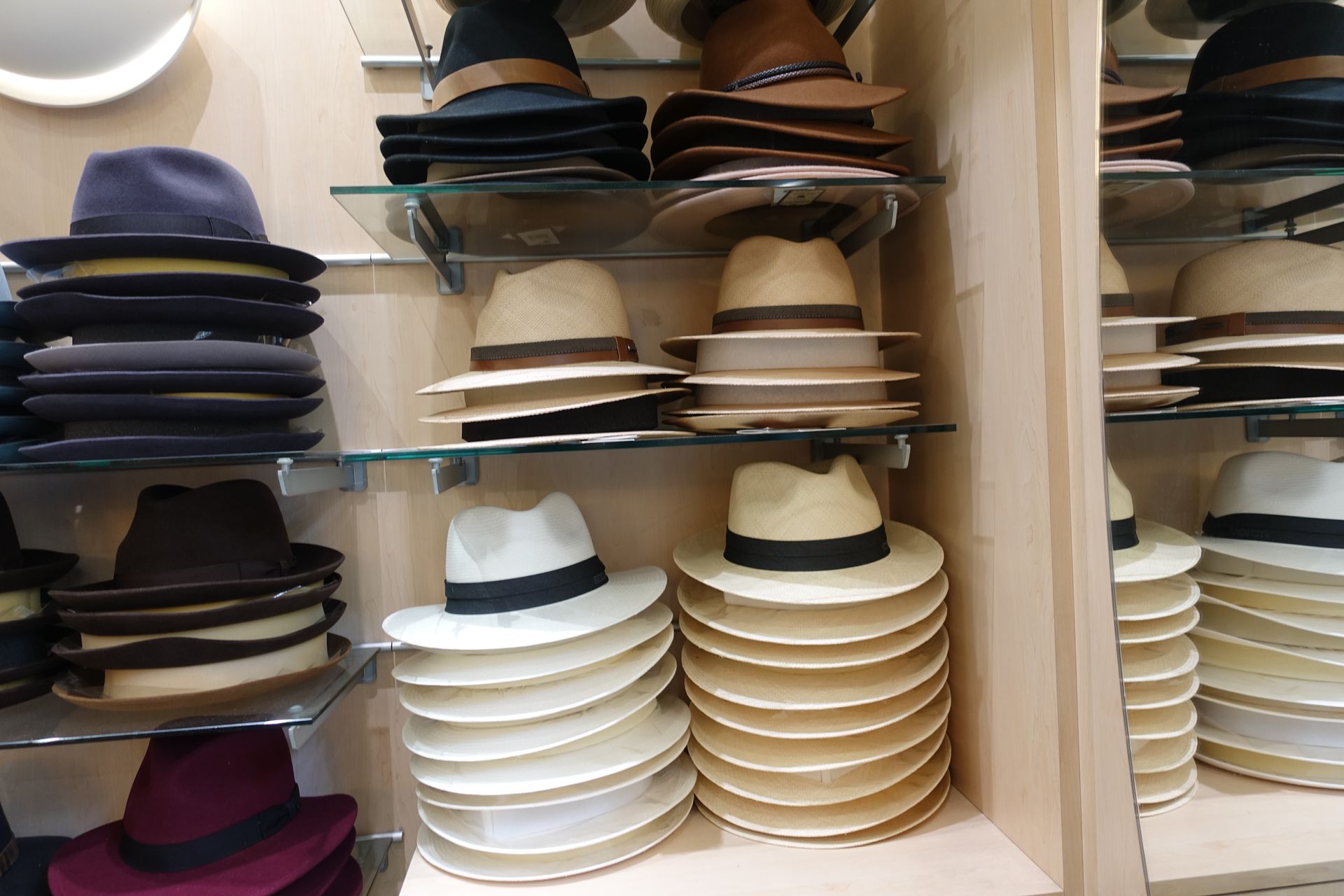 Des étagères remplies de chapeaux assortis de différentes couleurs, notamment blancs, beiges et bleu marine.