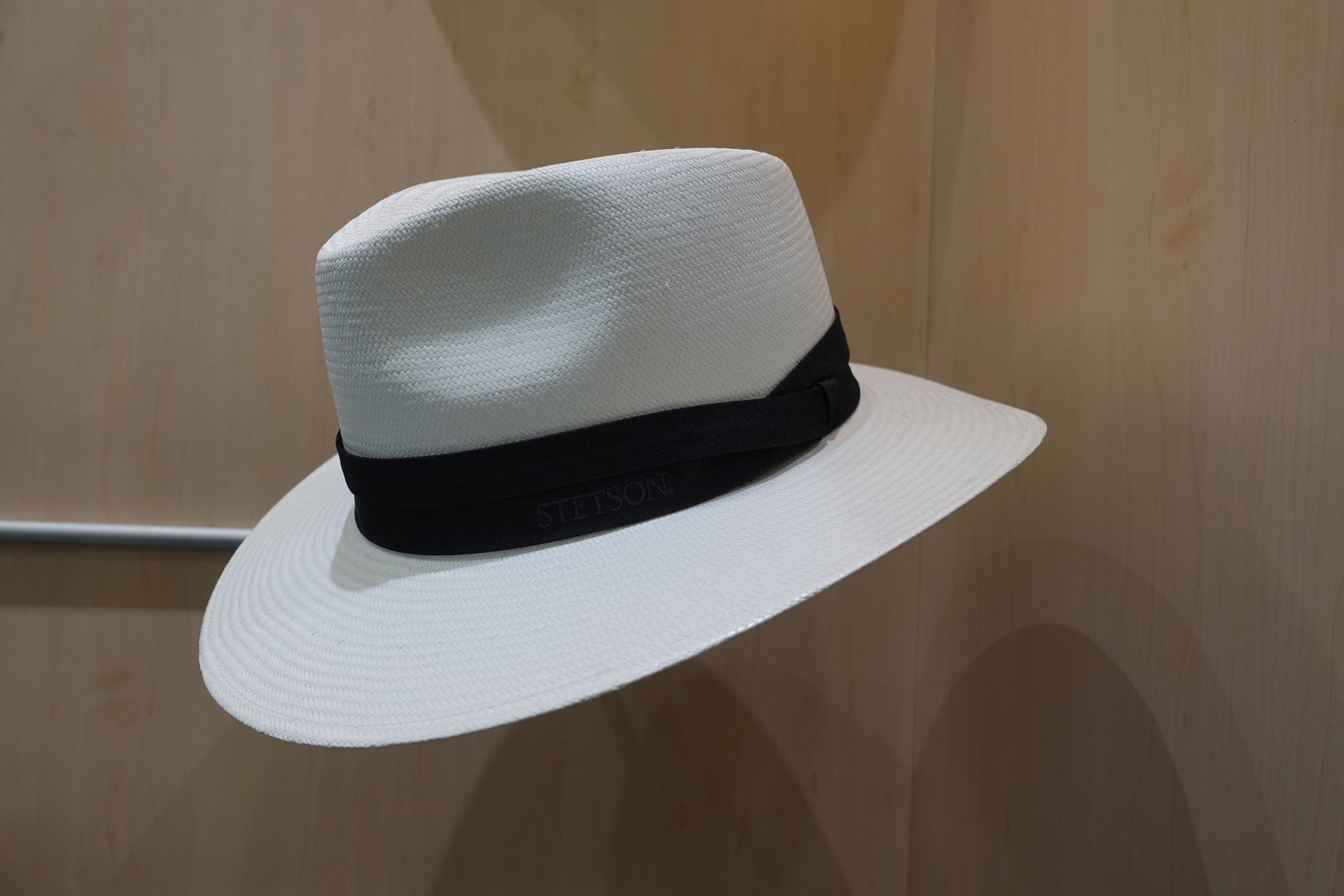 Fedora blanc à ruban noir sur fond de bois