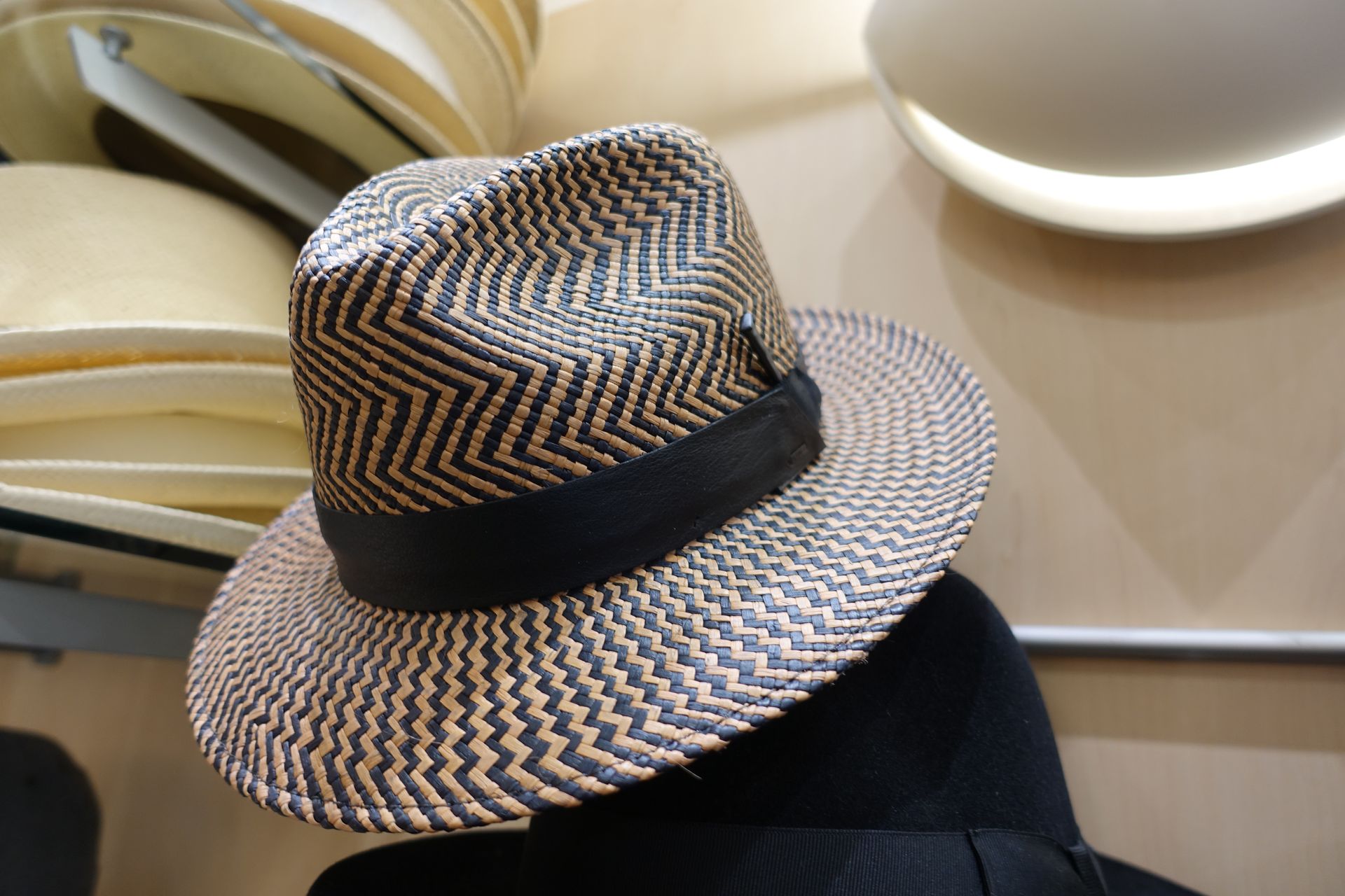 Chapeau de paille à ruban noir sur une étagère, vu du dessus