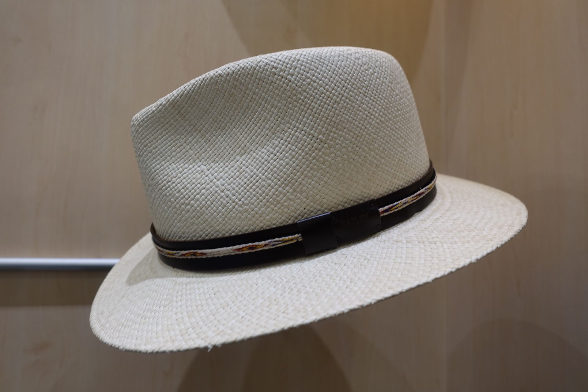 Chapeau fedora blanc tissé avec un ruban noir sur une surface en bois