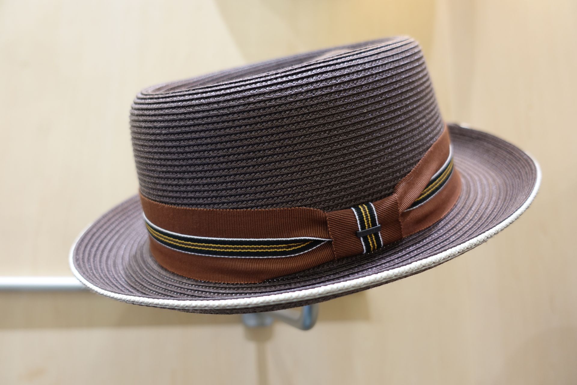 Chapeau fedora marron tissé avec un ruban, présenté sur fond clair