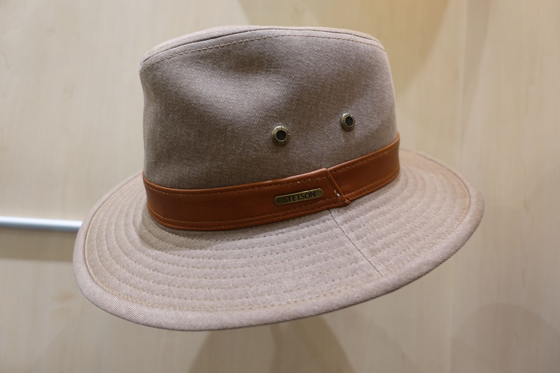 Chapeau beige clair à ruban marron, présenté sur fond uni