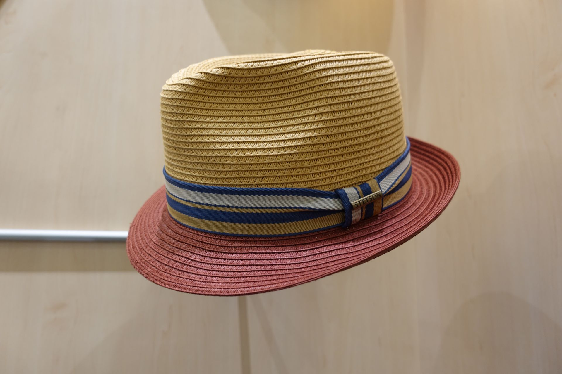 Chapeau de paille à bord rouge et ruban bleu sur fond beige uni
