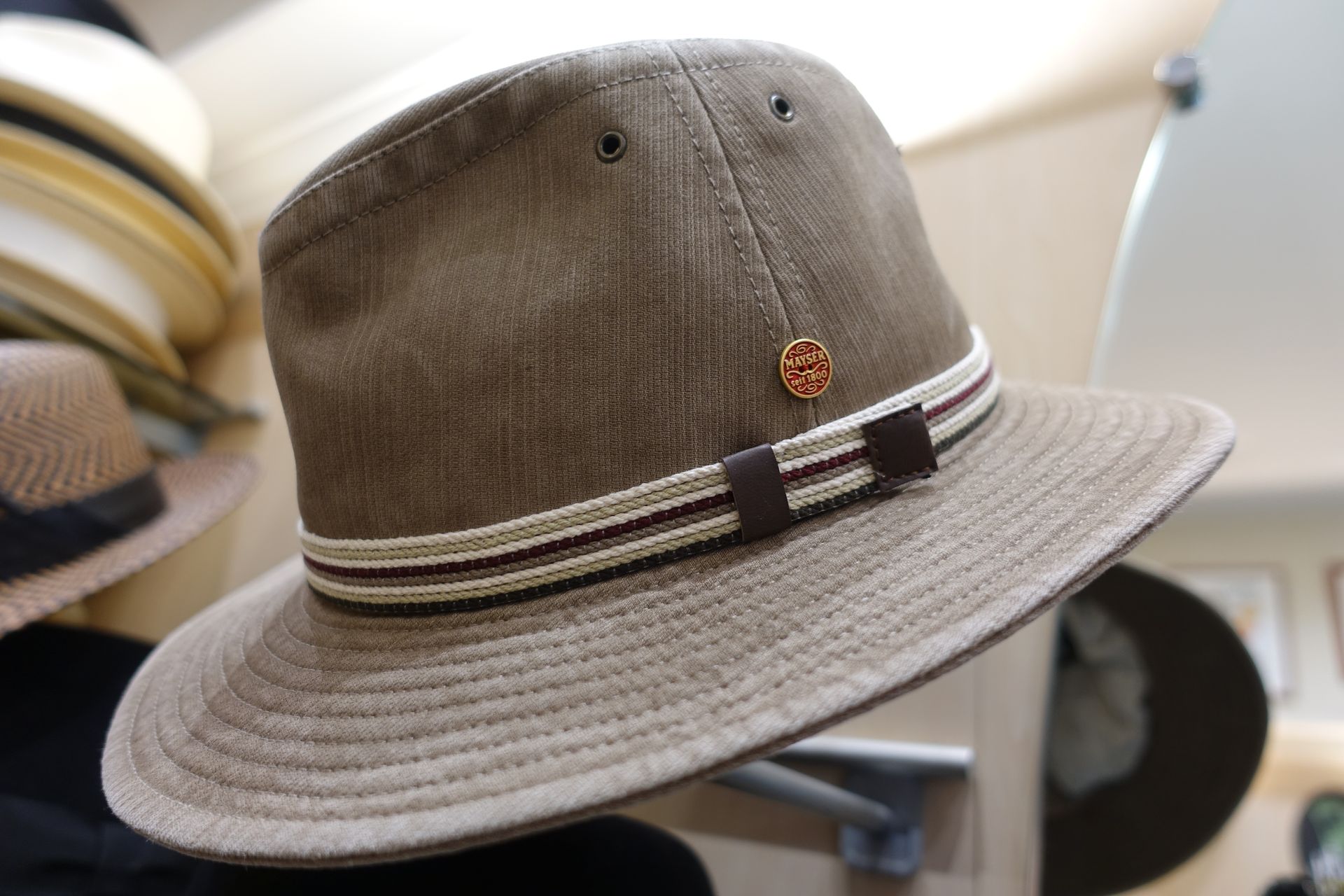 Chapeau fedora marron à bande rayée et petit emblème sur une étagère