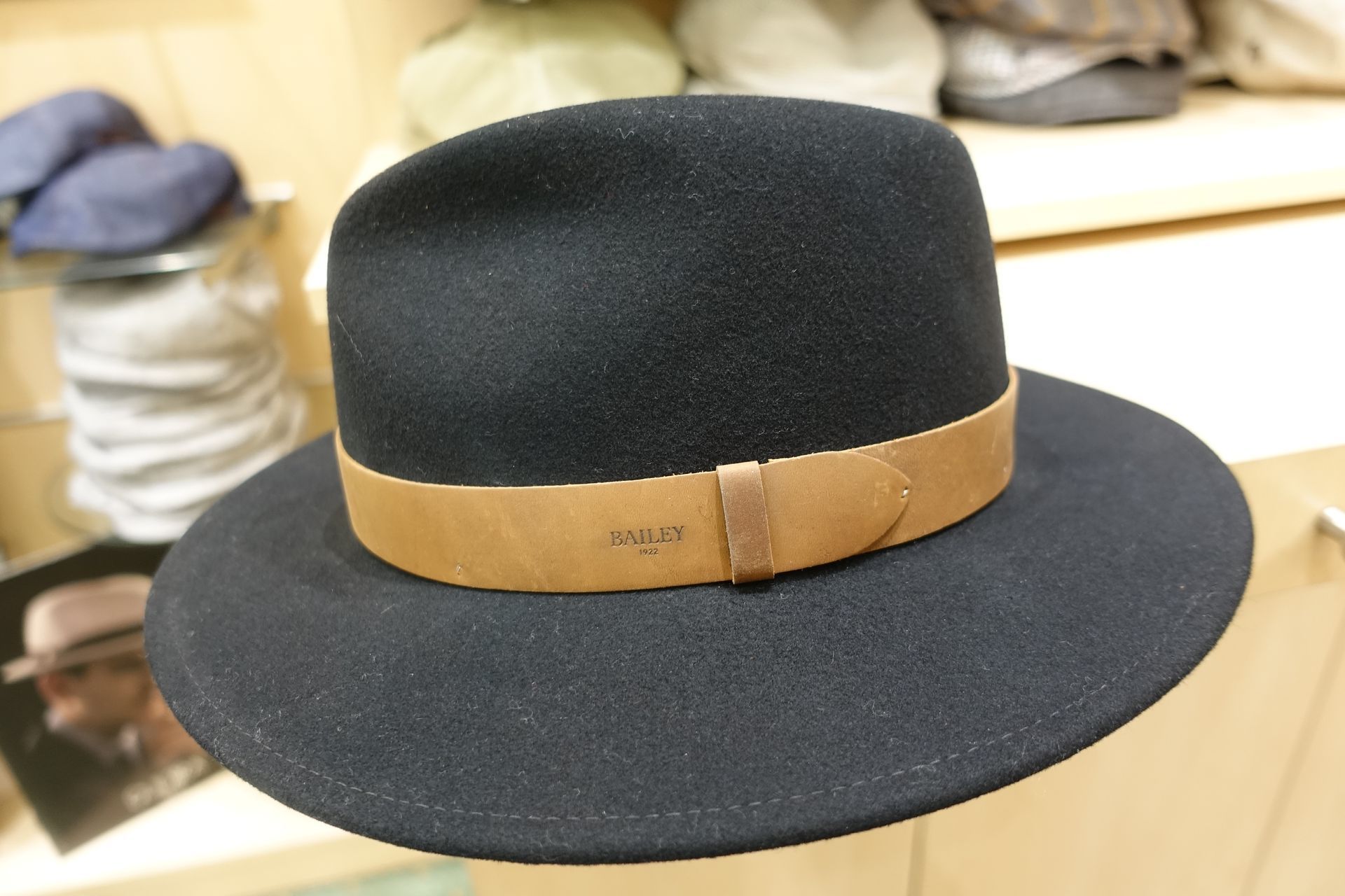 Chapeau en feutre noir avec un ruban beige exposé sur une table dans un magasin