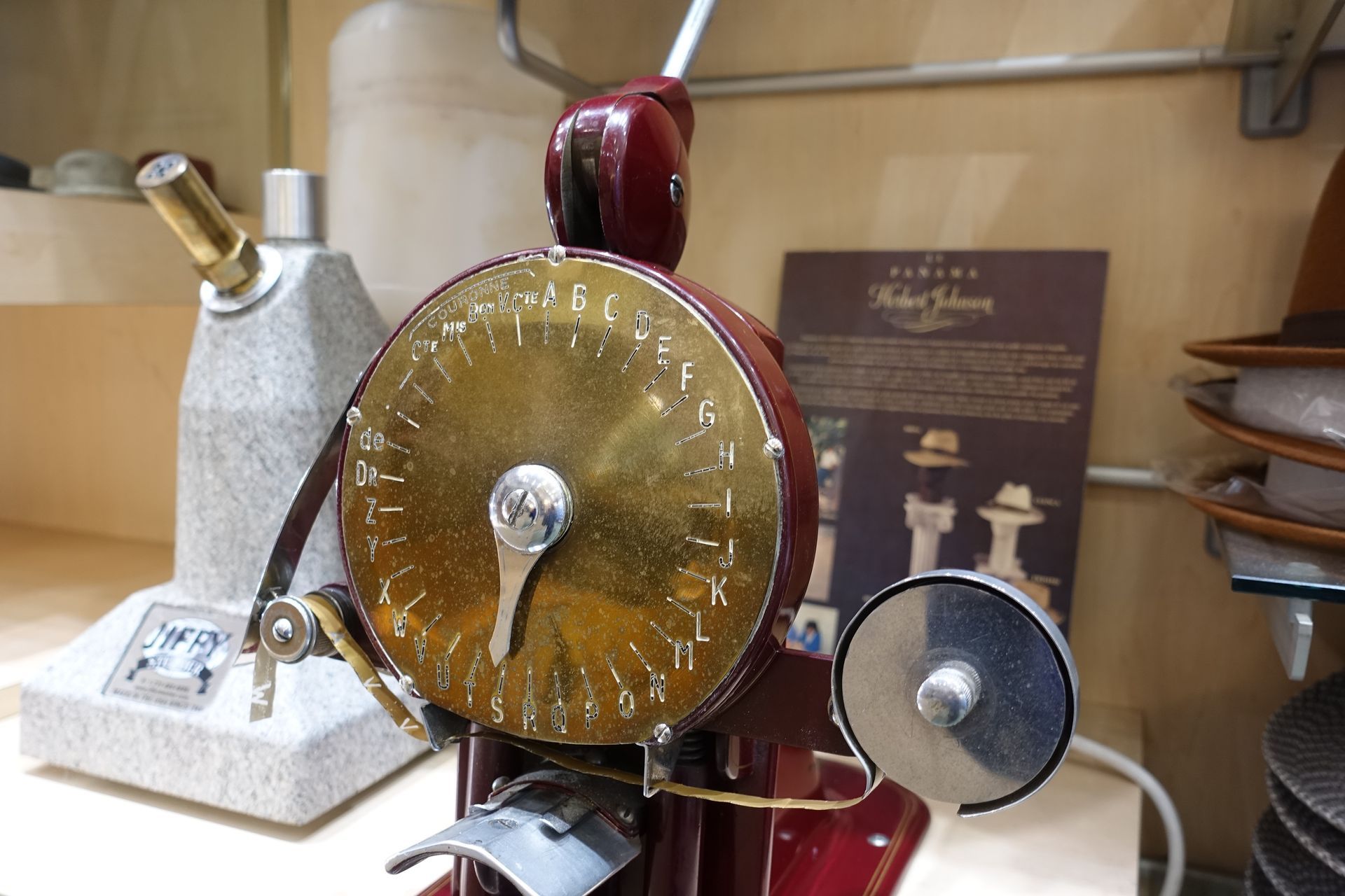Machine à coudre vintage en laiton et bordeaux avec un grand cadran circulaire exposée