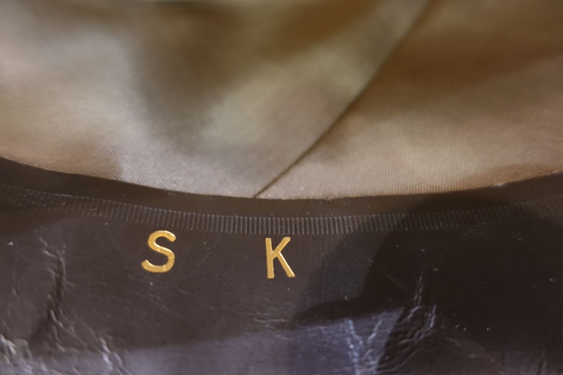 Tissu noir avec les lettres dorées « S » et « K » brodées près du bord