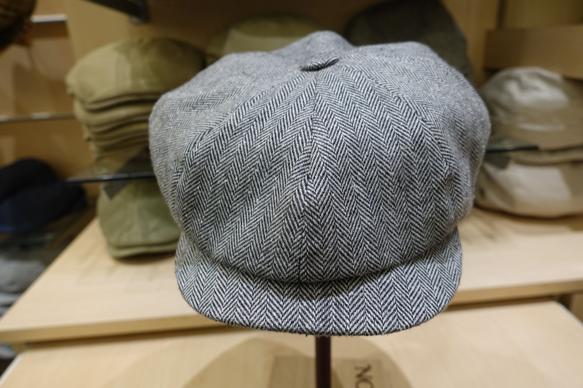 Casquette gavroche grise à chevrons sur un présentoir dans une chapellerie