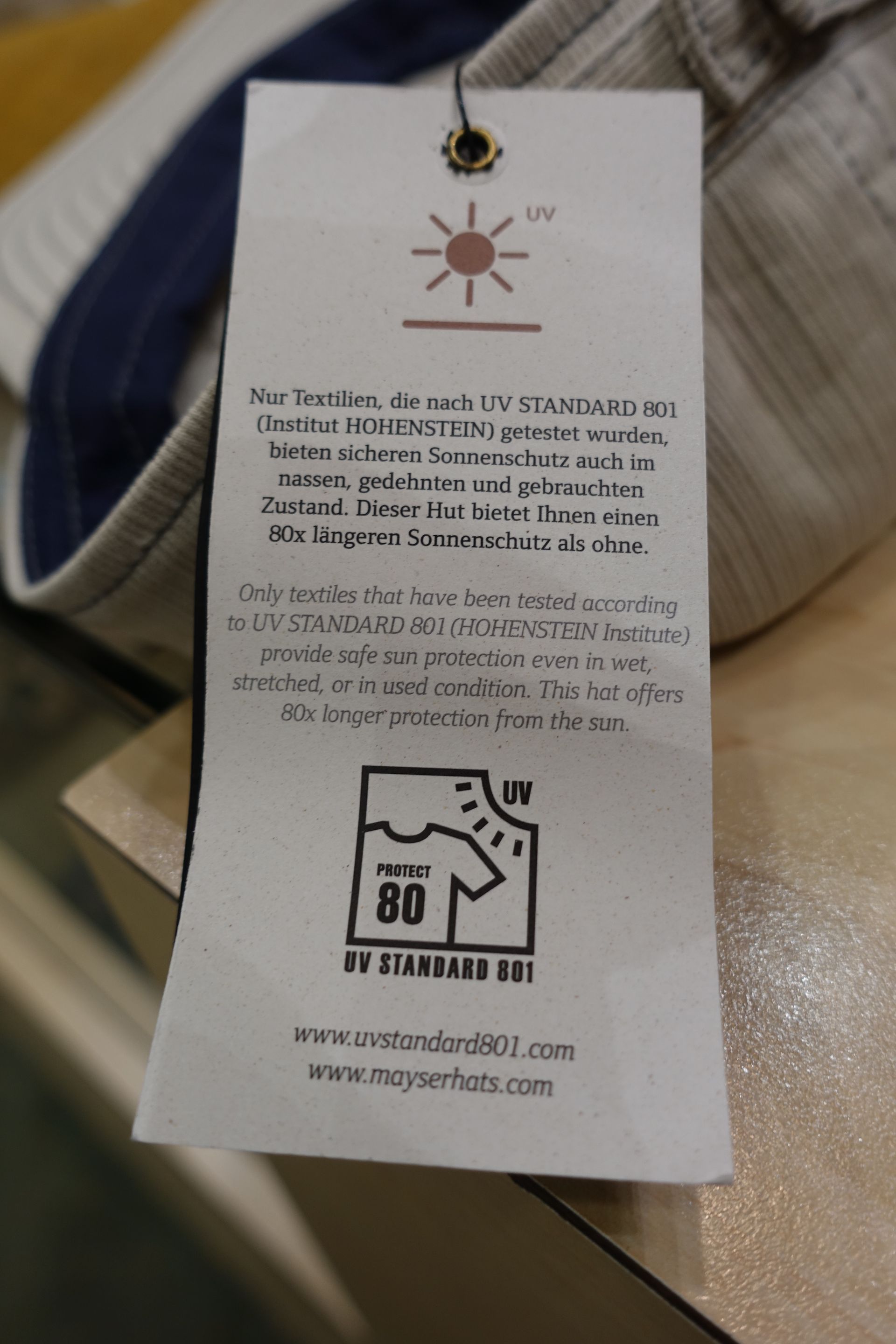 Étiquette blanche accrochée à un vêtement en maille, avec les instructions d'entretien et un logo recyclé « 80 ».