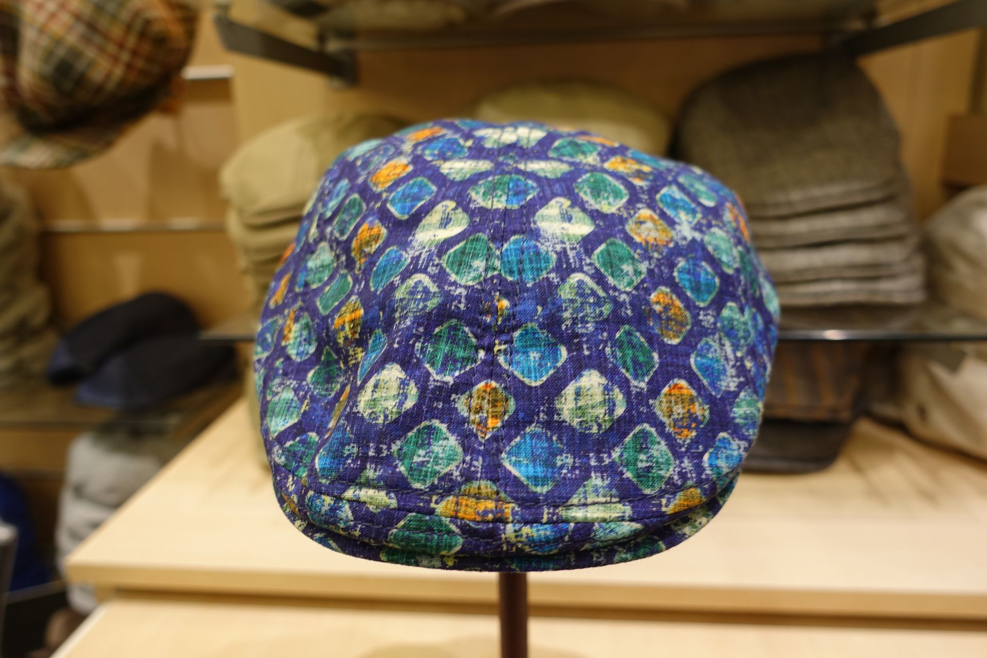Béret à motifs bleus et verts exposé en magasin