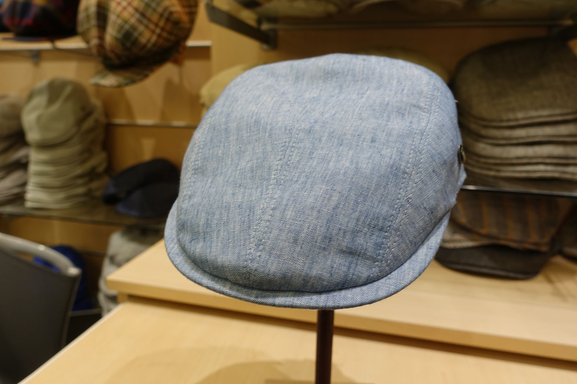 Casquette plate bleu clair exposée sur une étagère dans une chapellerie.