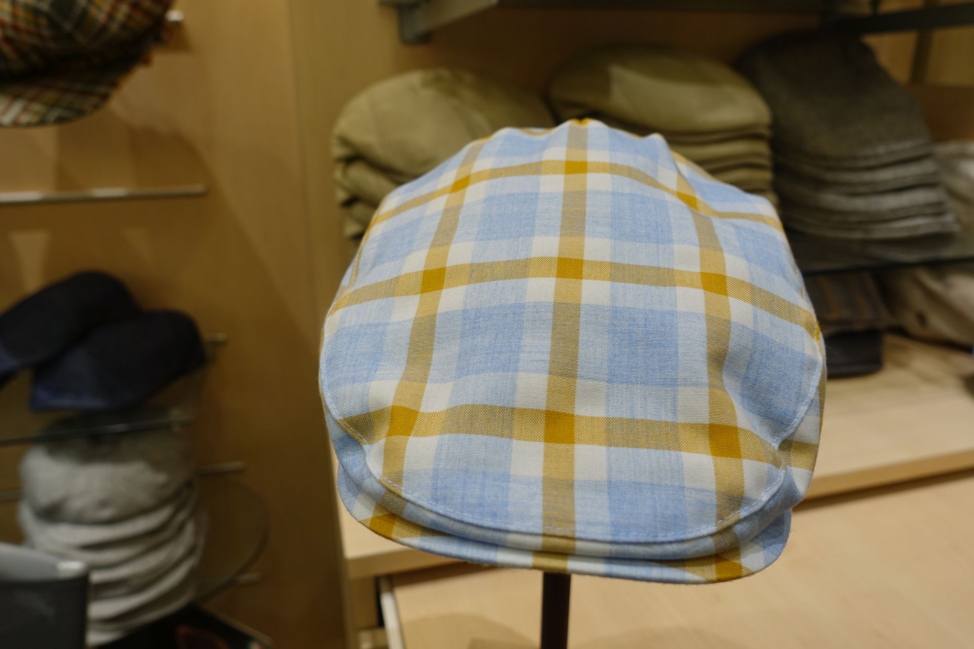 Casquette plate à carreaux bleus et jaunes sur un présentoir dans un magasin de vêtements