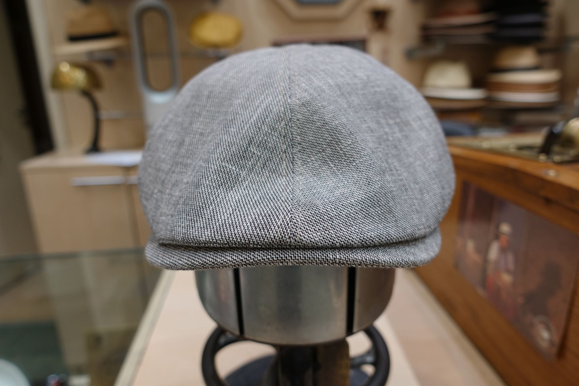 Bonnet gris tricoté sur un présentoir dans un magasin, avec des étagères de chapeaux en arrière-plan.