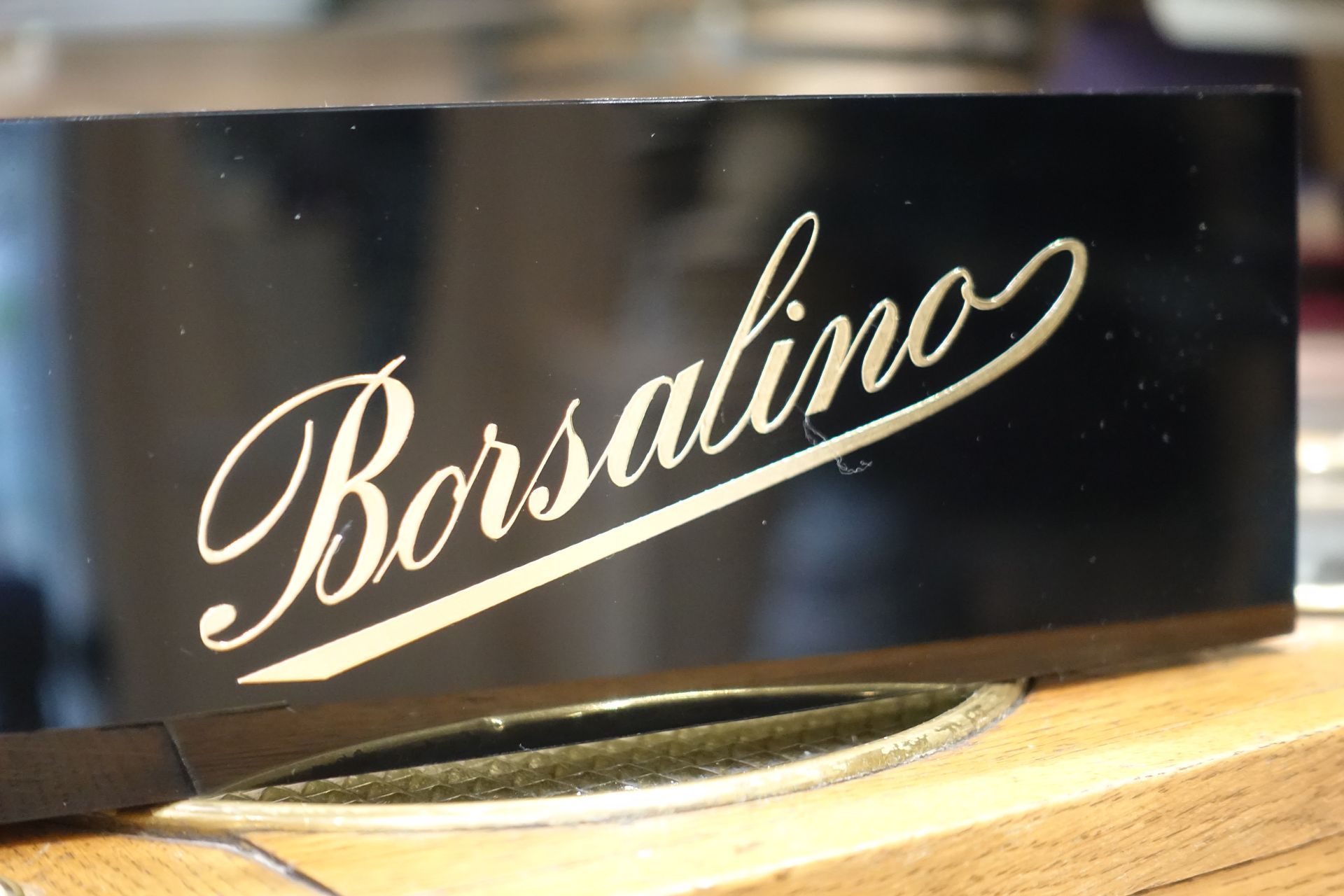 Panneau noir avec l'inscription « Borsalino » en écriture cursive crème sur une surface en bois
