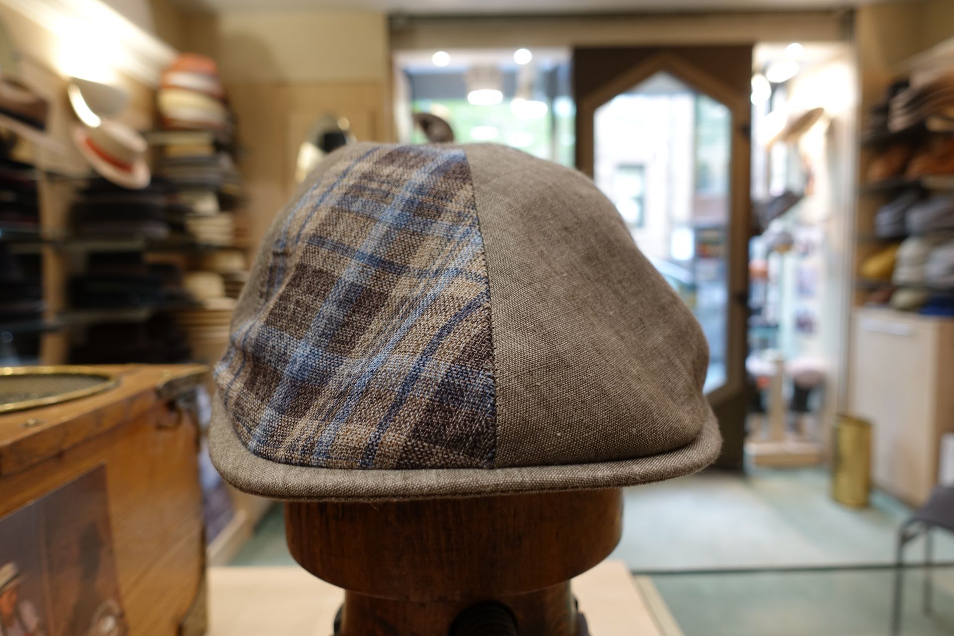 Casquette en tweed à carreaux sur un support en bois dans l'intérieur d'une boutique à l'éclairage tamisé