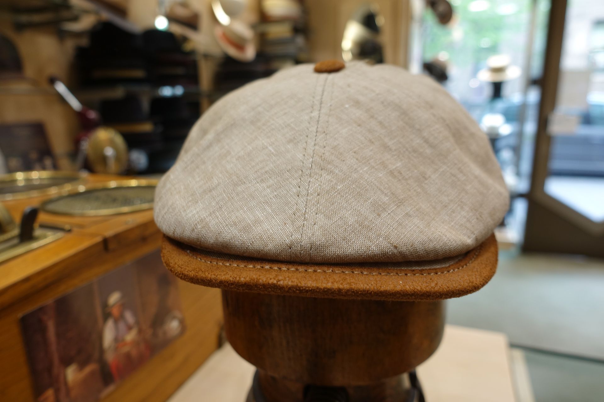 Casquette plate en laine beige sur un présentoir en bois dans une vitrine