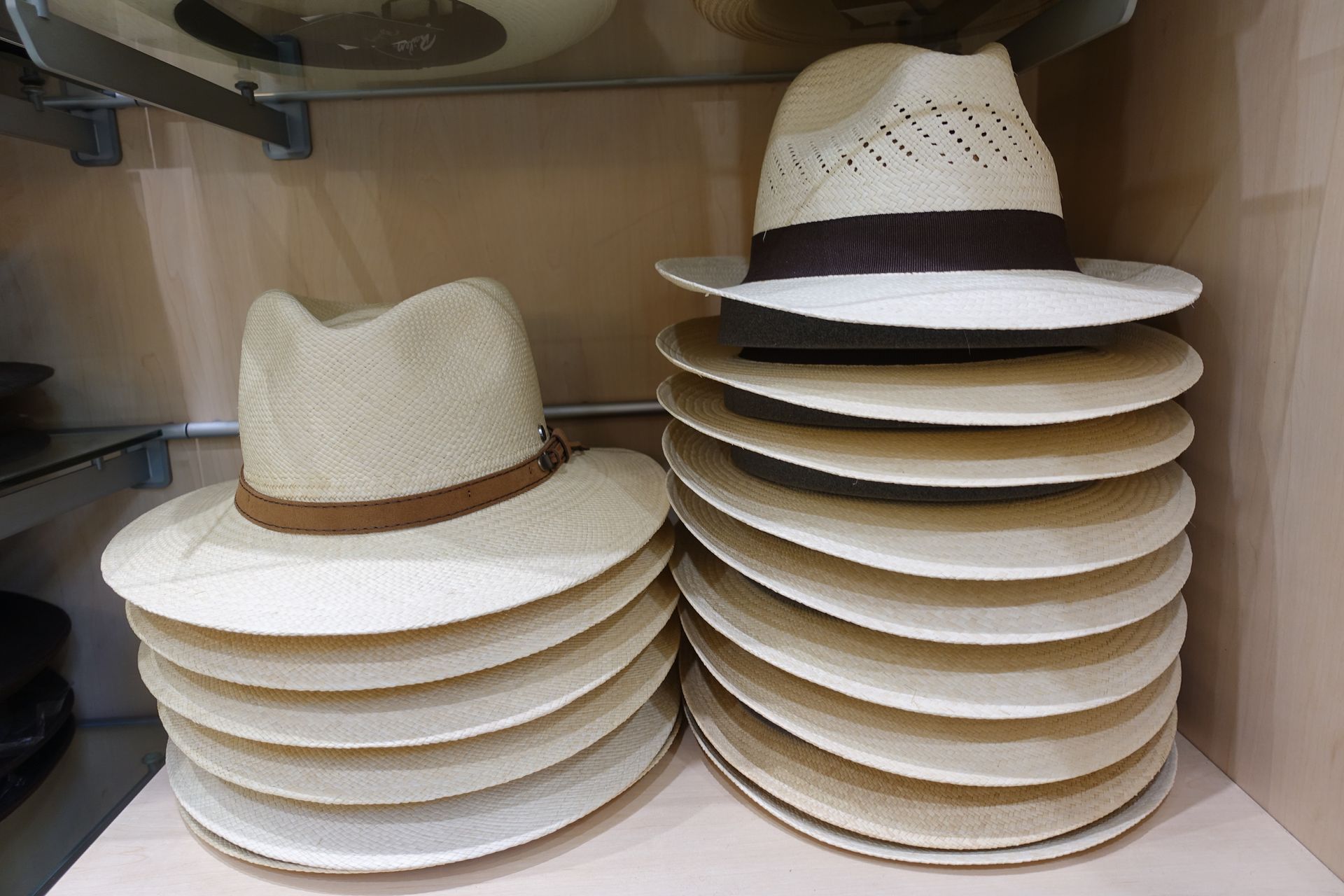 Des piles de chapeaux de paille blancs à rubans marron sur une étagère