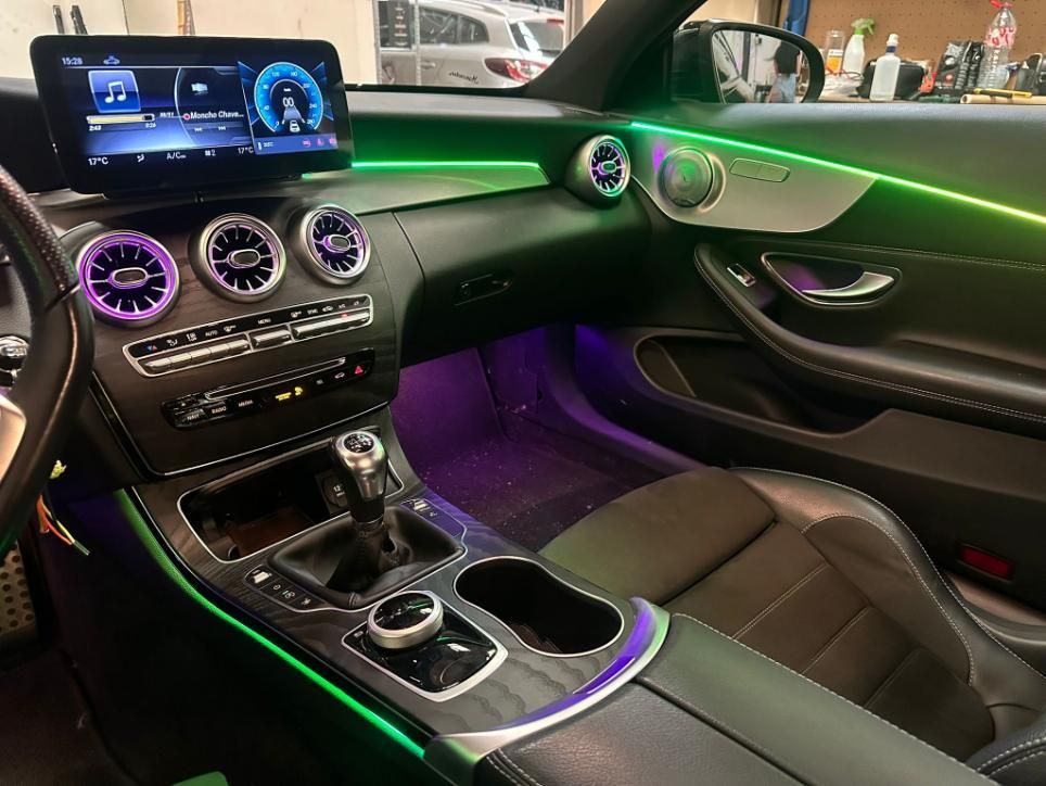 Interior de Mercedes con iluminación LED de colores. El tablero, la consola, los asientos y la iluminación ambiental brillan.