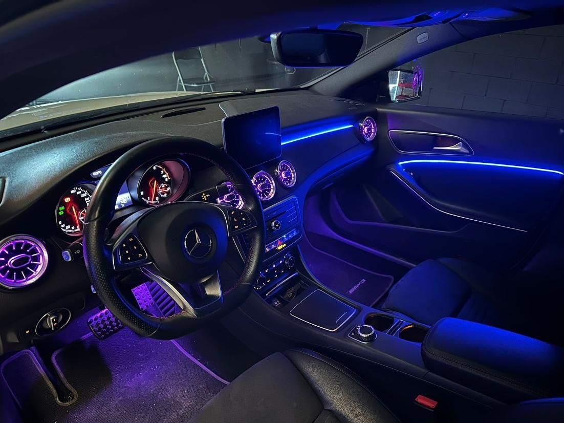Interior del coche con iluminación ambiental azul que ilumina el tablero, el volante y la consola.