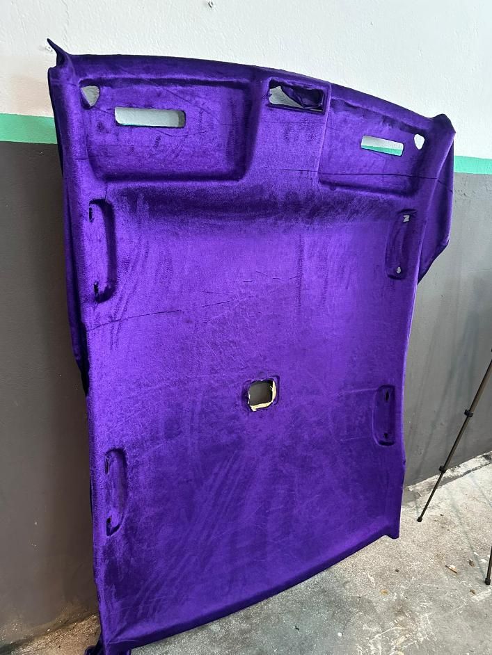 Revestimiento de techo de coche en terciopelo morado, forma curva, con recortes para manijas y luces.