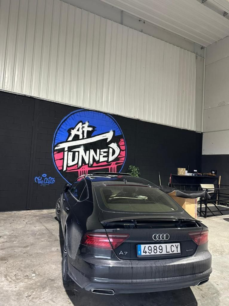 Sedán Audi negro estacionado dentro de un garaje; logotipo 