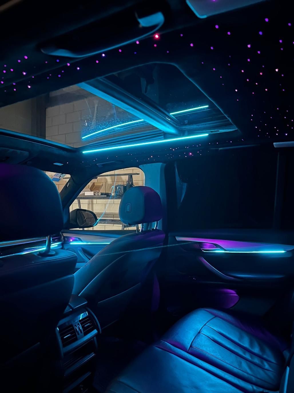 Interior de un automóvil con luces LED azules y violetas que iluminan los asientos, el techo y el techo corredizo.