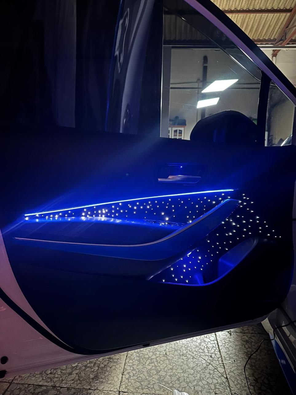 Interior de la puerta del automóvil con iluminación LED tipo estrella azul.