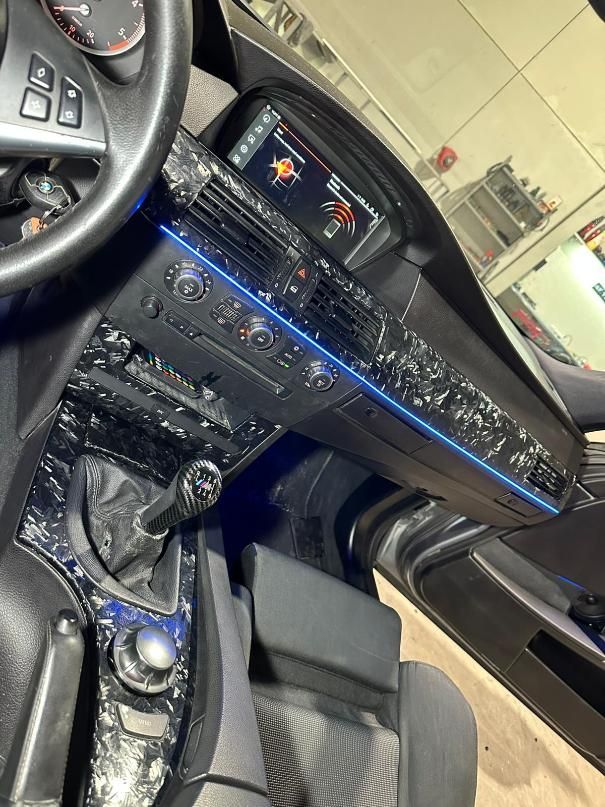 Interior del coche con tablero, palanca de cambios y asiento modificados. Iluminación azul. Detalles en negro y plata.