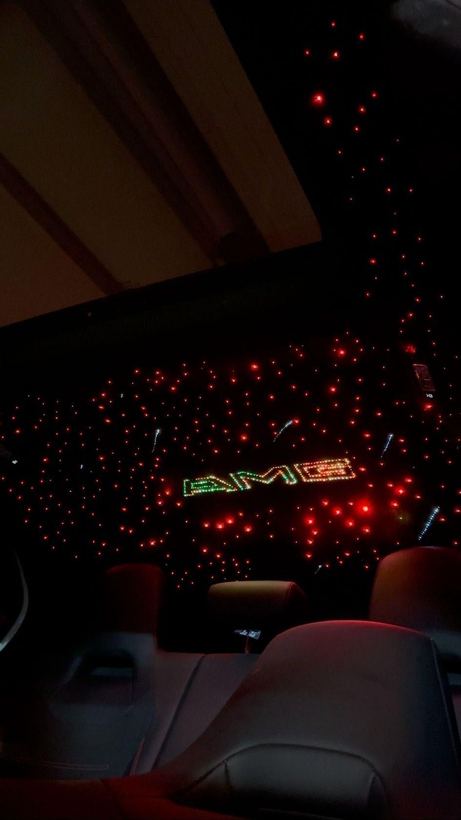 Techo interior del vehículo con luces de fibra óptica de color rojo y logotipo “AMG” iluminado.