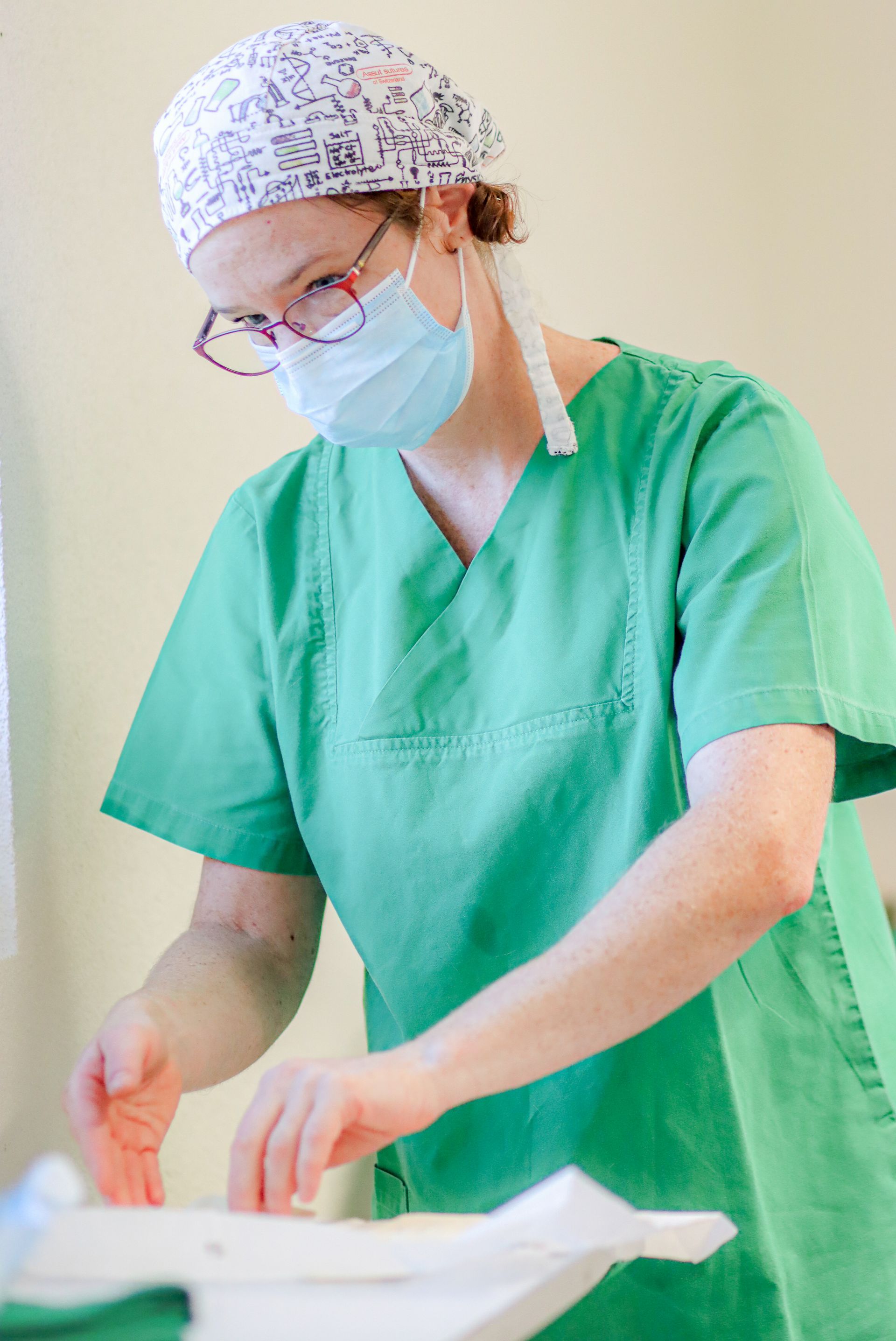 Une chirurgienne portant un masque et des lunettes se prépare pour une intervention chirurgicale.