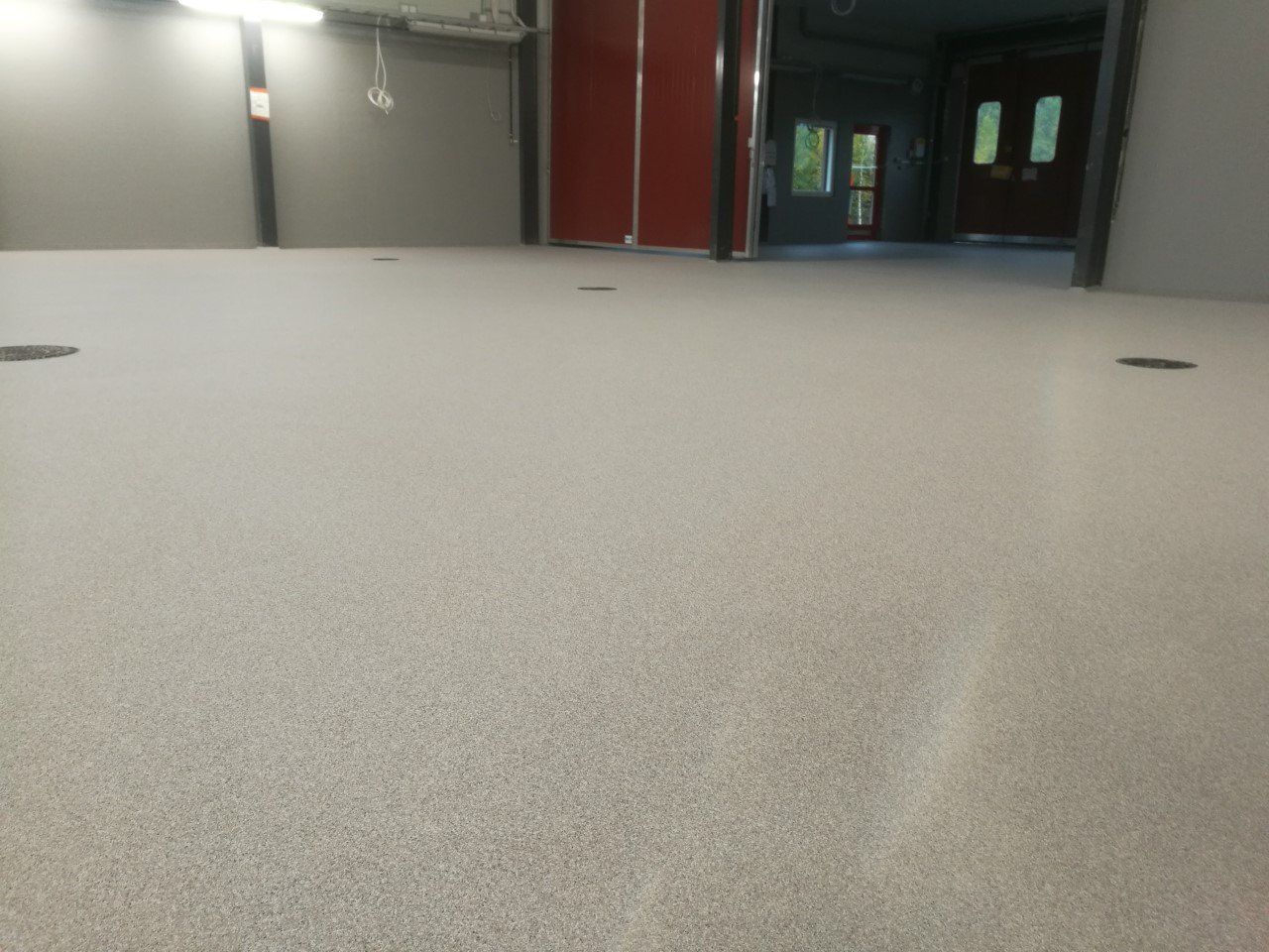 Vaaleanharmaa täplikäs epoksilattia keskeneräisessä huoneessa.