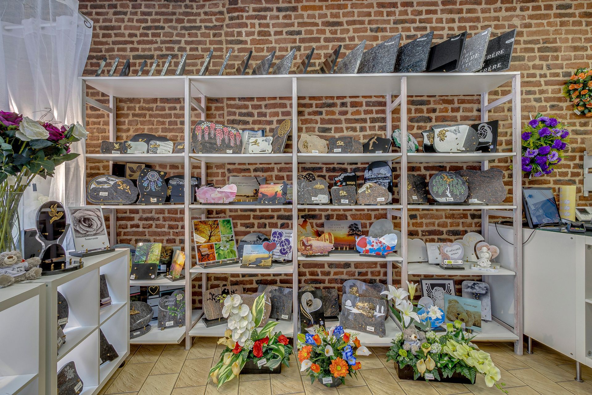 Étagères avec des plaques funéraires et des bouquets de fleurs