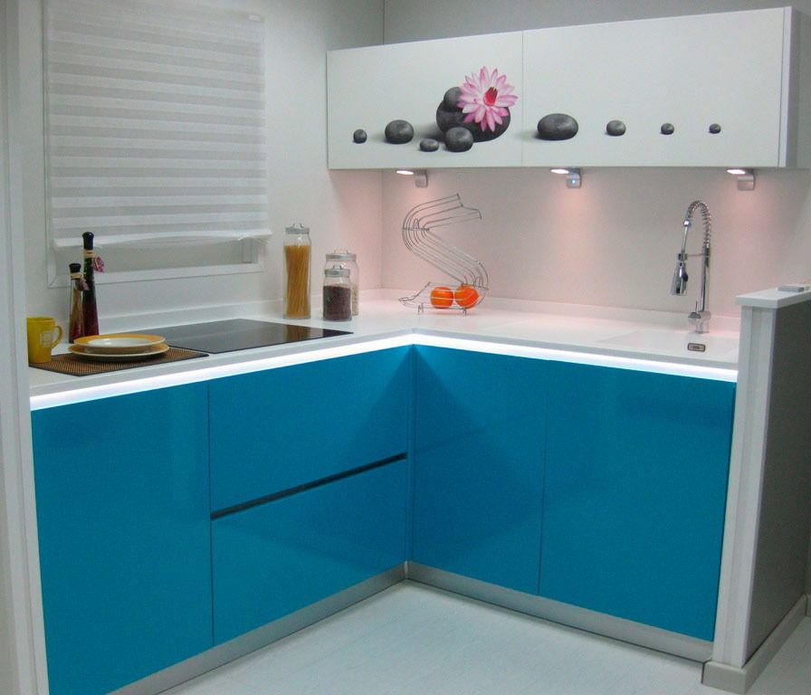 Cocina moderna en color azul y blanco con gabinetes superiores con diseño floral e iluminación debajo de los gabinetes.