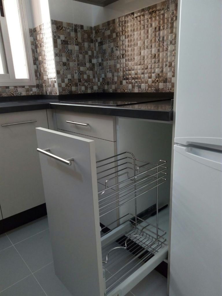 Mueble de cocina extraíble con estantes de alambre cromado, contra salpicadero de azulejos y encimera negra.