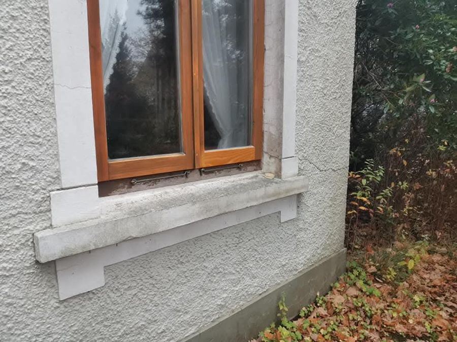 Ein Fenster an der Seite eines Hauses mit einem Holzrahmen.