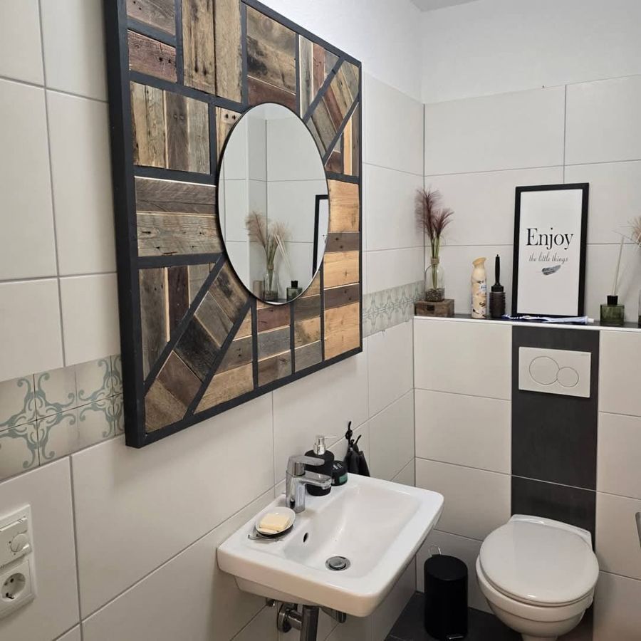Ein Badezimmer mit einem Waschbecken, einer Toilette, einem Spiegel und einem Schild mit der Aufschrift „Genießen“