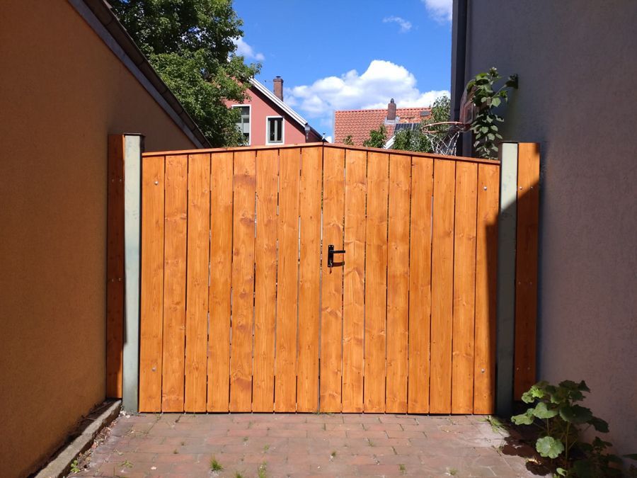 Ein Holztor ist zu einer gemauerten Auffahrt hin geöffnet