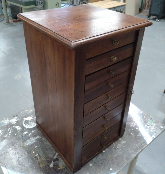 Drei Männer arbeiten in einer Werkstatt an einem Stück Holz.