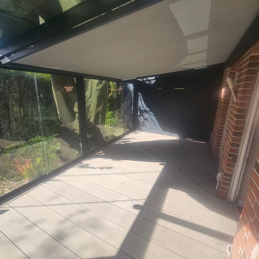 Eine Terrasse mit Glasdach und Ziegelmauer.