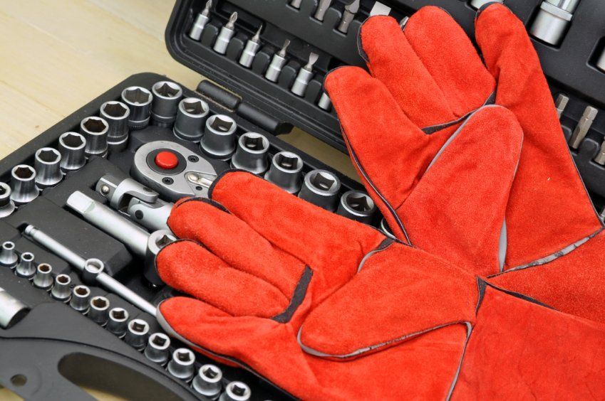 Un par de guantes de soldadura rojos sobre una caja de herramientas.