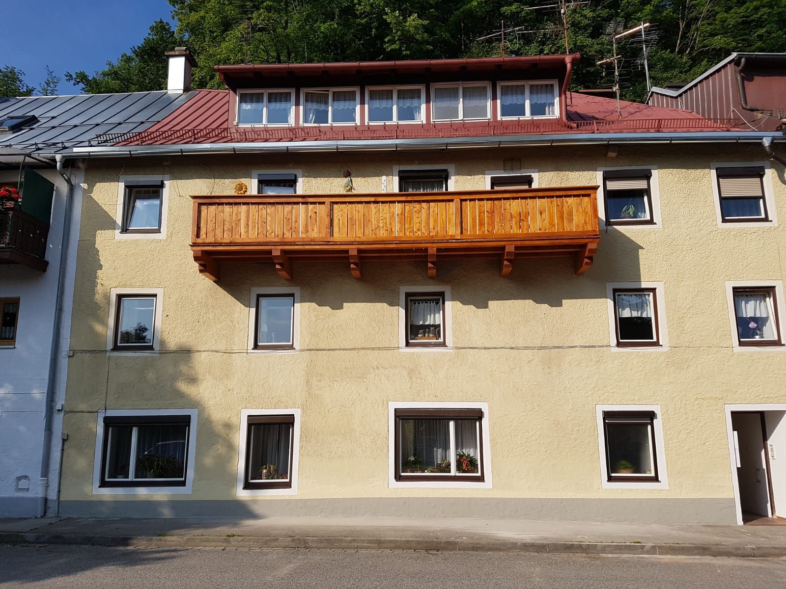 Balkon aus hellem Holz an Wohnhausfassade in traditioneller Bauweise
