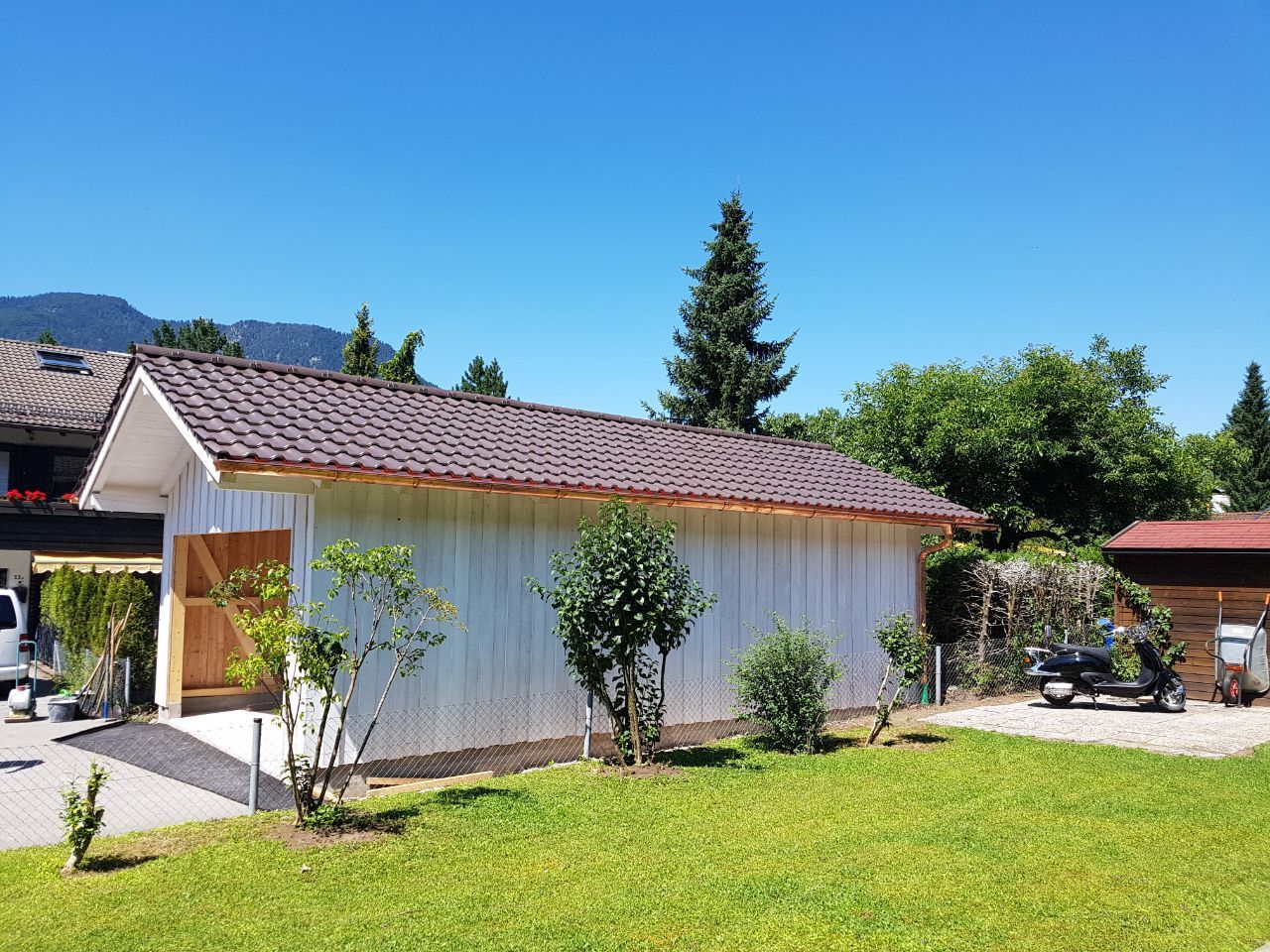 Freistehender Holzcarport mit Satteldach in grünem Garten