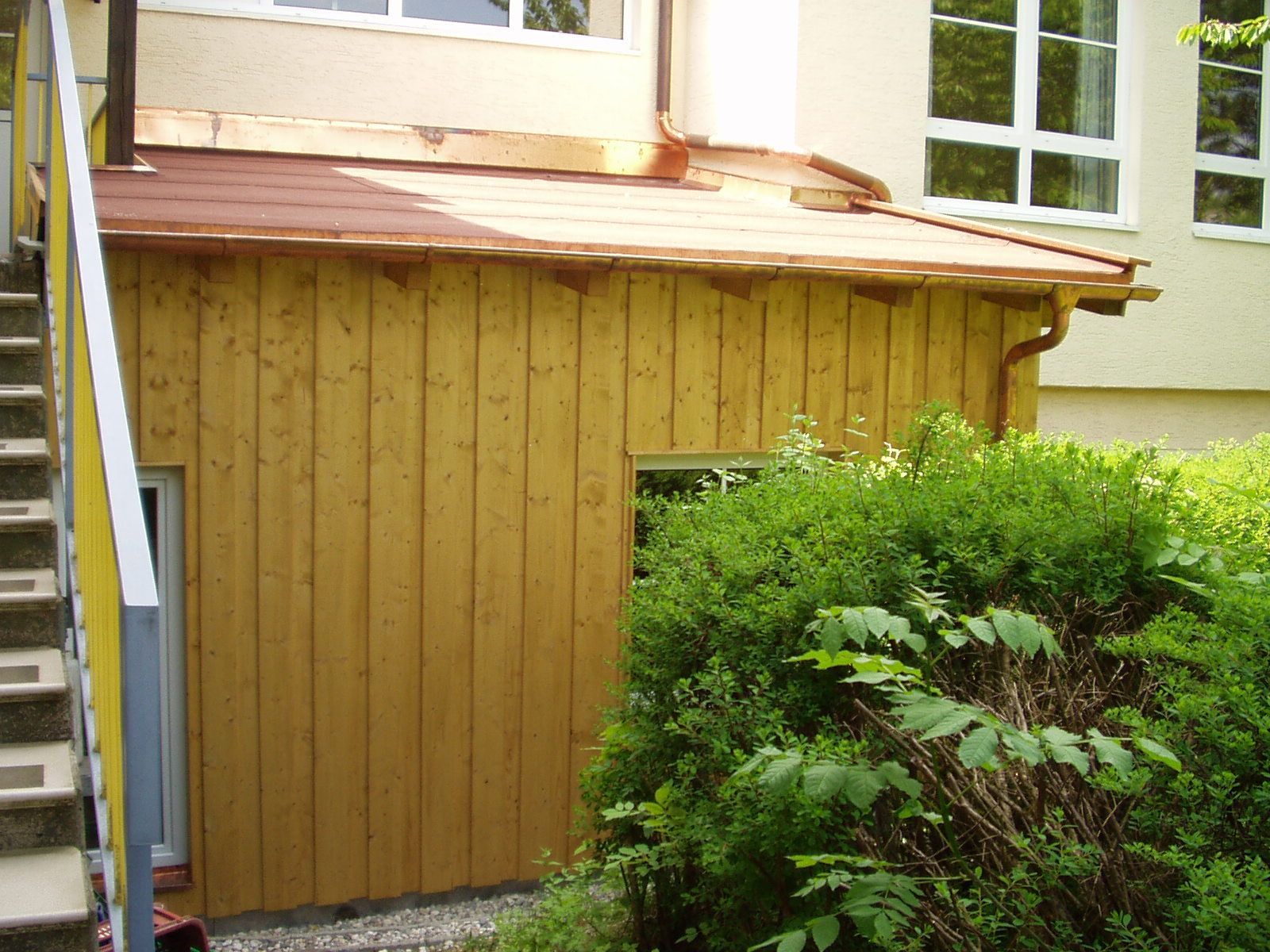 Holzfassade mit Fenster und bepflanzter Umgebung