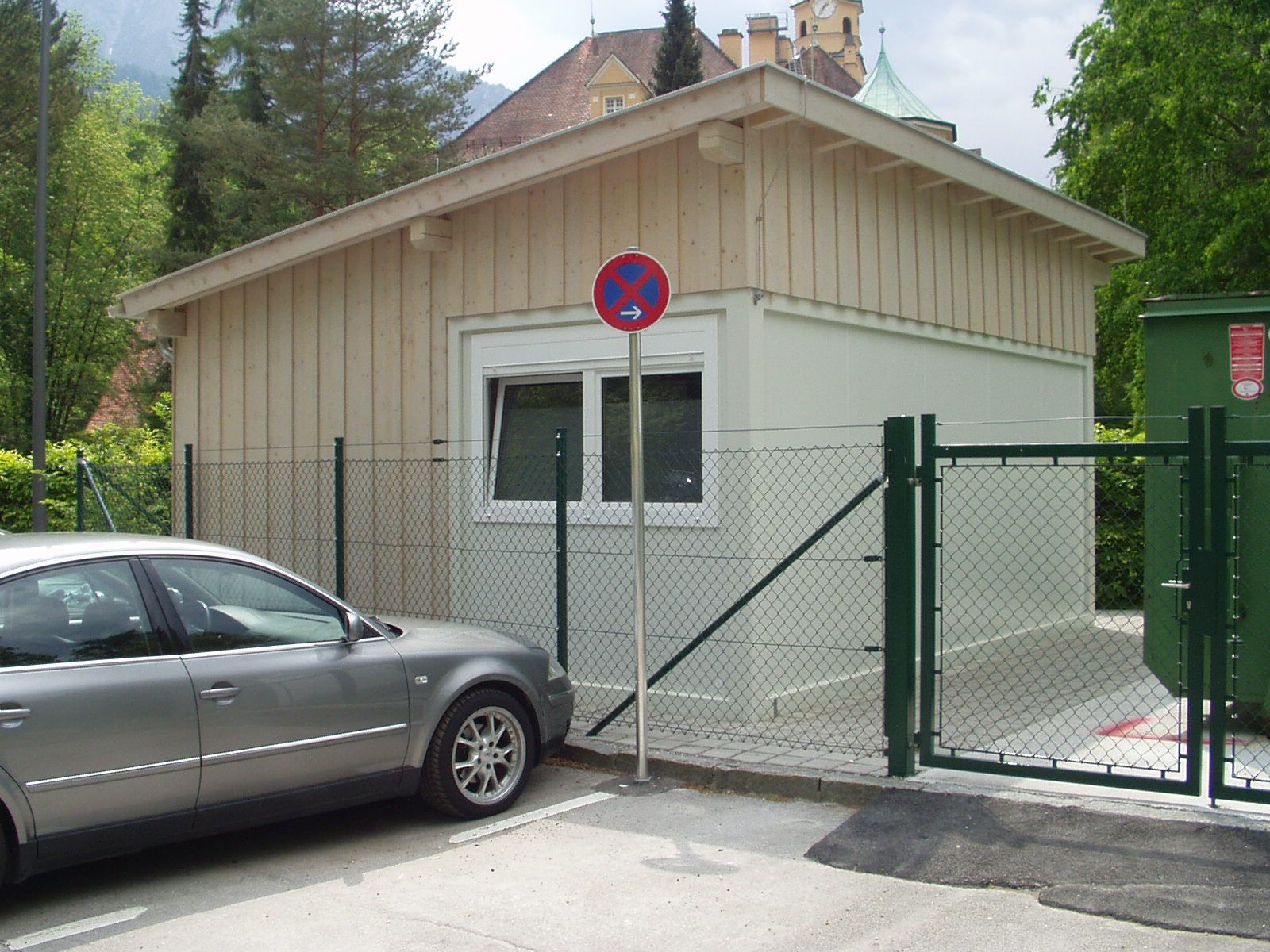 Einfahrtstor aus Metall und Holz vor Gartenhaus