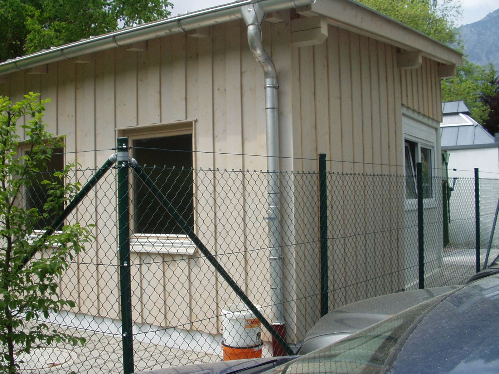 Holzverkleideter Anbau mit Regenrinne und Zaun